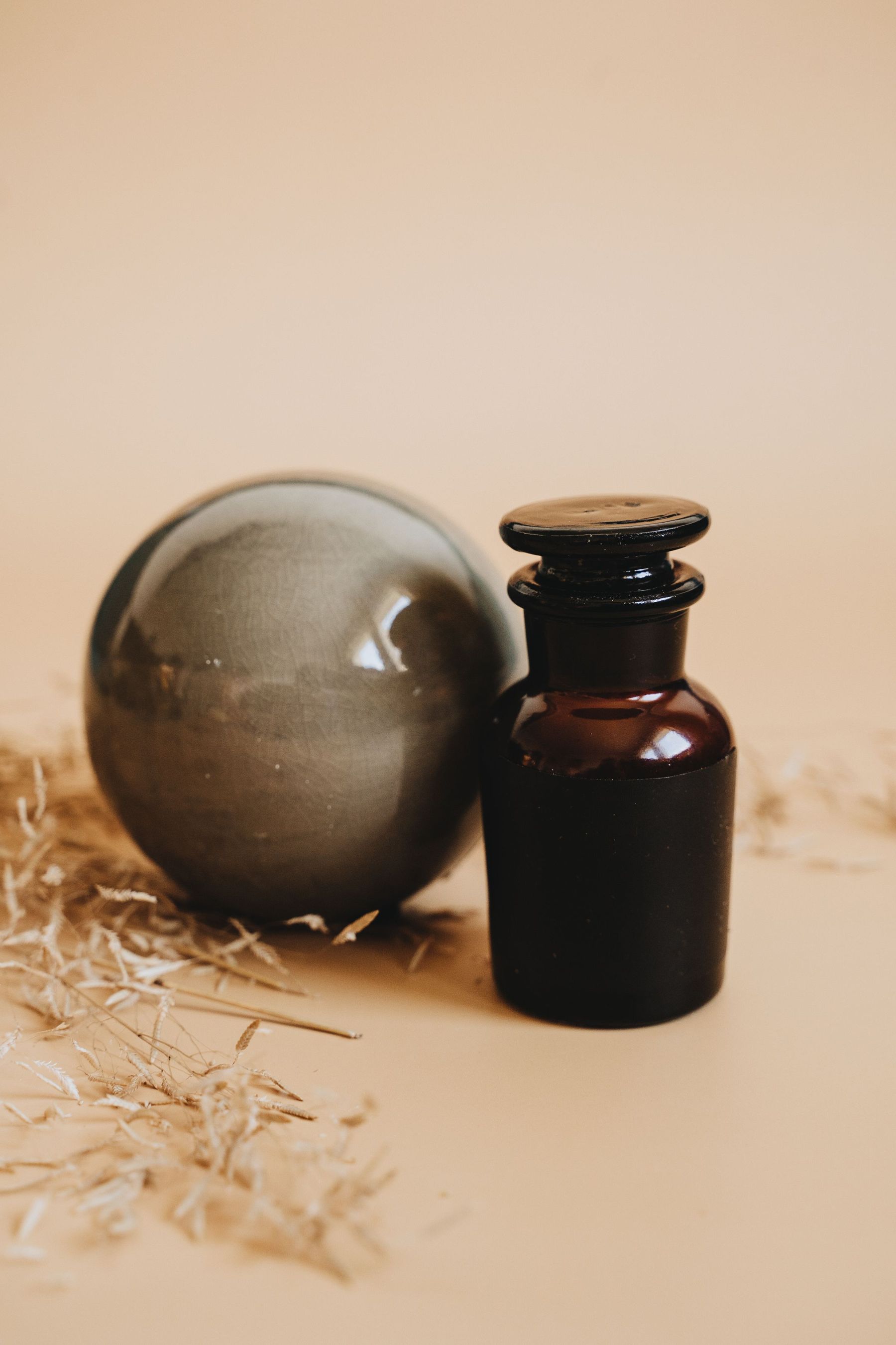 An amber bottle beside a stone sphere